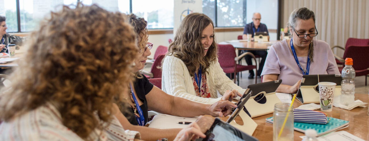 An image of a group of women talking. They are around of the table seated.