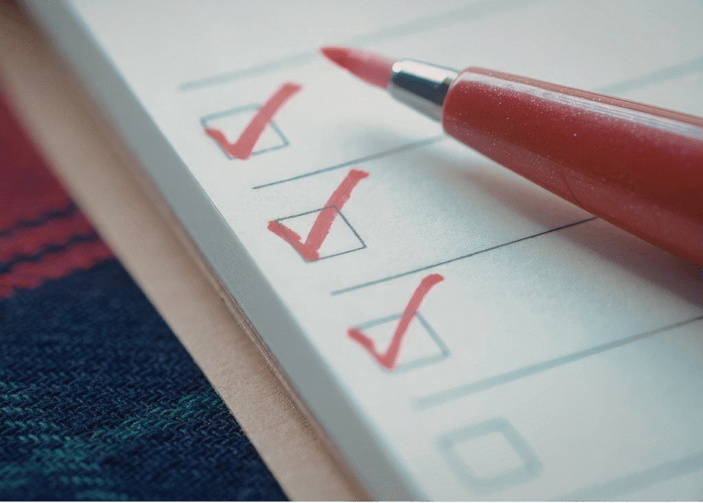 a red pen resting on a notepad with hand-drawn checkboxes
