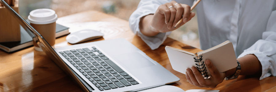 Student or faculty member working on a laptop with a notebook ready for course planning