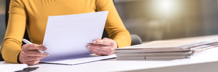 Close-up of a person reviewing and signing academic documentation